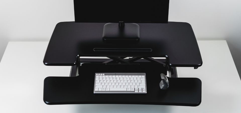 Close-up of the black Adjustable Sit-Stand Desk Riser 2 with two platforms, featuring a DXT mouse and an UltraBoard 950 keyboard.