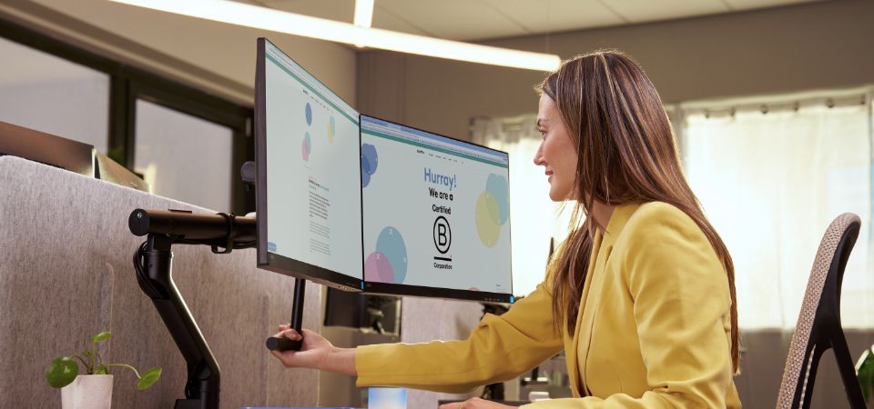 Woman adjusts her monitor to the correct height with an ergonomic monitor arm for better posture and less neck strain.